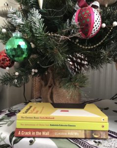 A stack of three books under a Christmas tree, all by Argentinian women writers.
