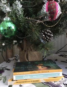 A stack of books under a Christmas tree, all books are new from indie publishers